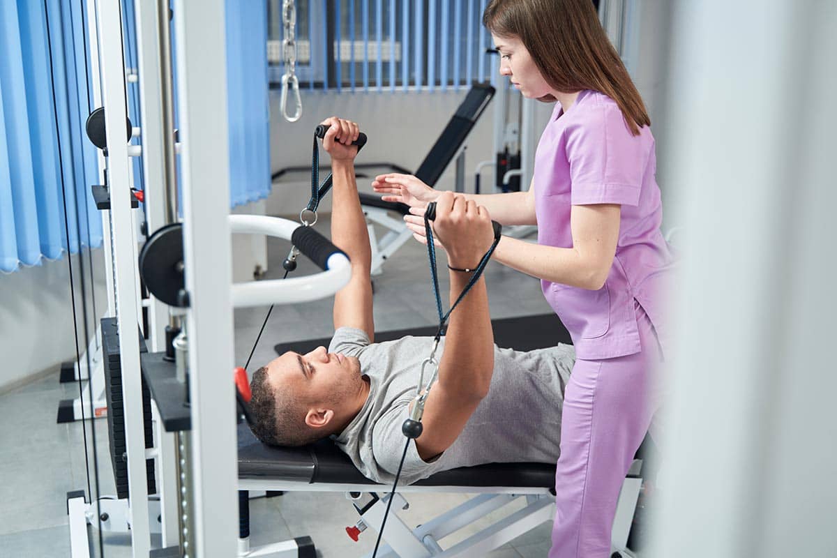 man doing physical therapy exercise with doctor