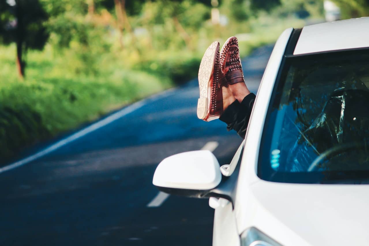 two feet resting out of the drivers seat car window