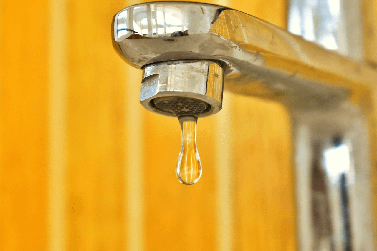 A dripping tap in front of a yellow wall