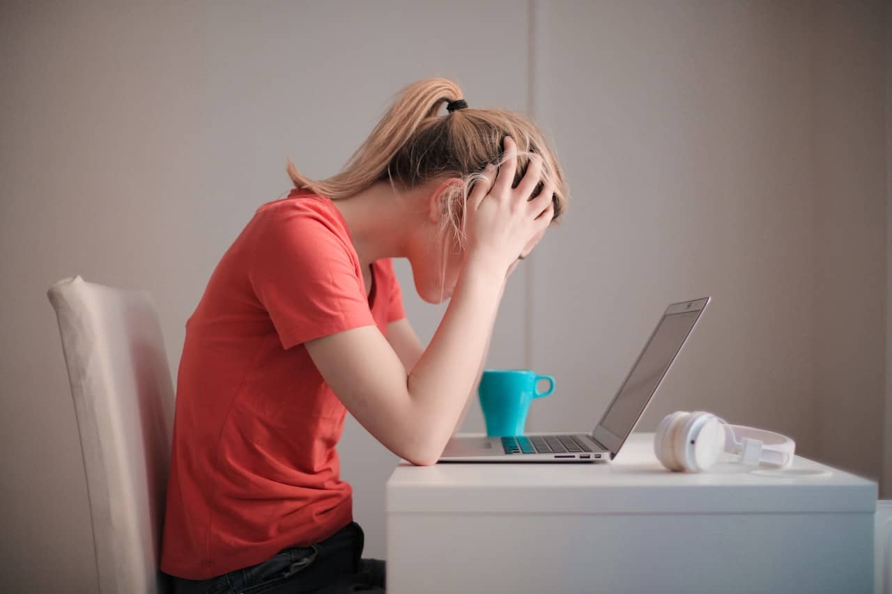 A woman looking stressed at their laptop