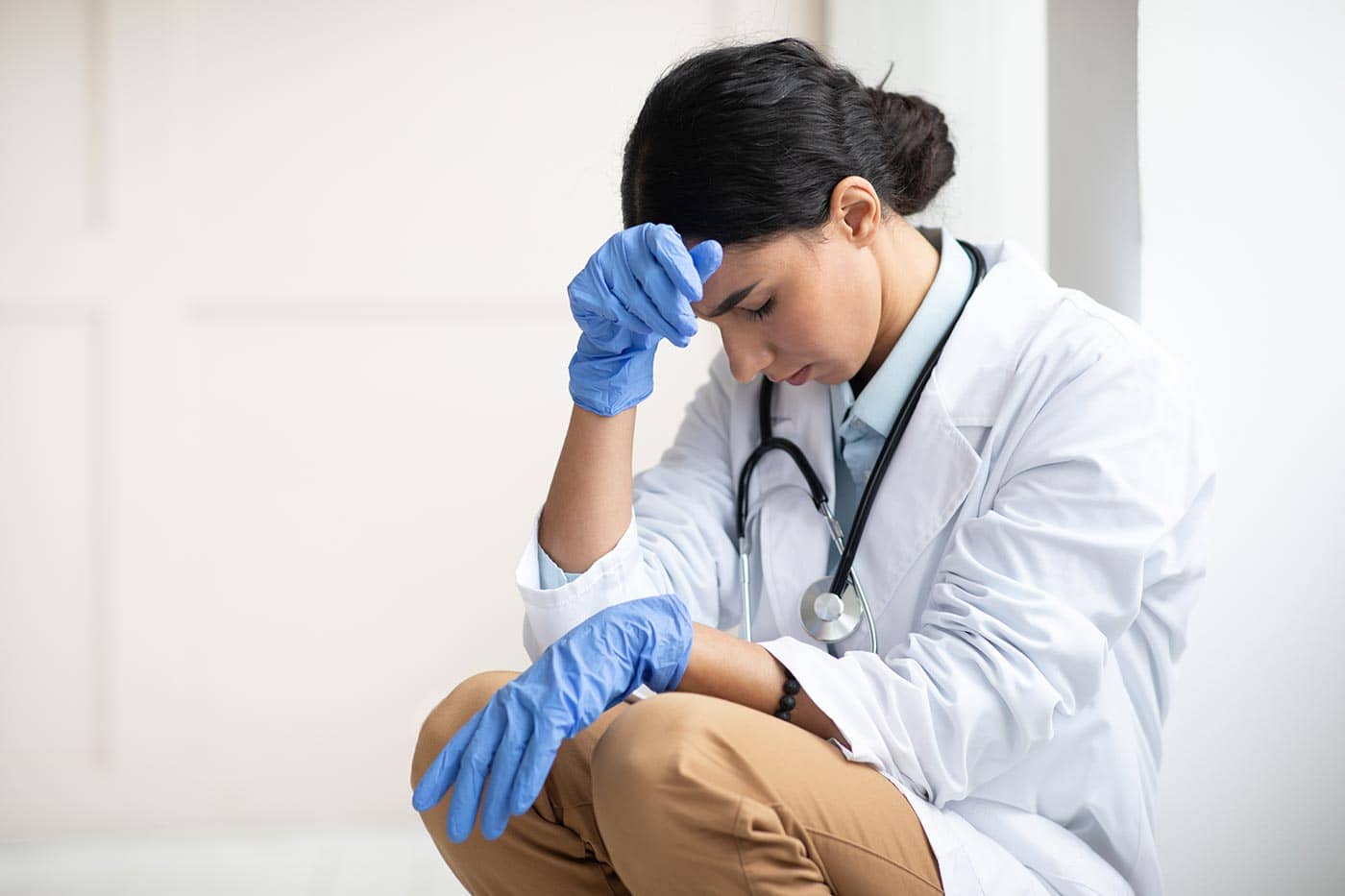 upset female doctor sitting next to wall