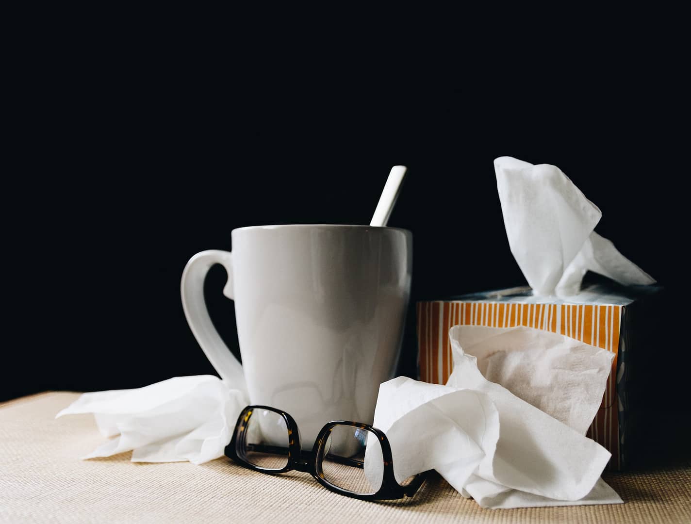 tissues and a mug on a bedside table