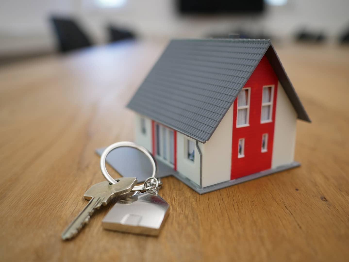 keys next to a minature house on a table