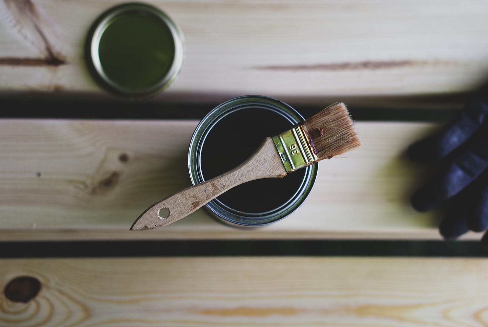 An open tin of paint with a paintbrush resting on top