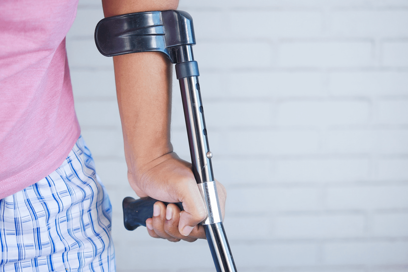 A close up image of a woman leaning on one crutch