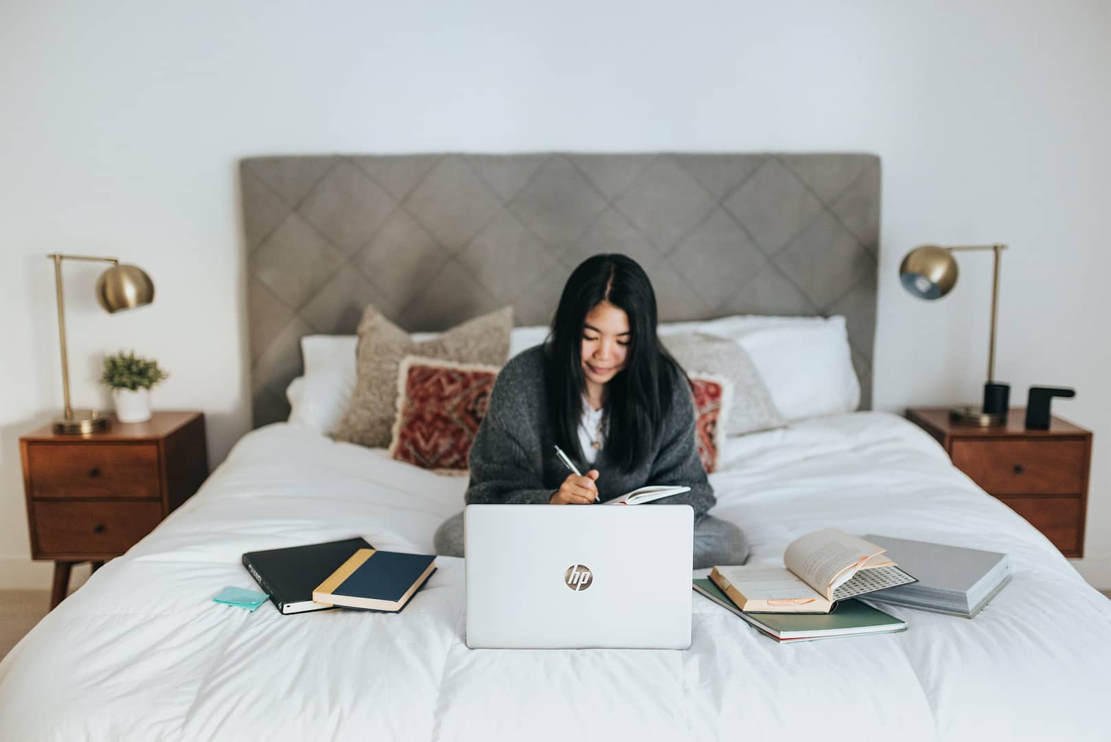 Someone with a laptop and books on their bed