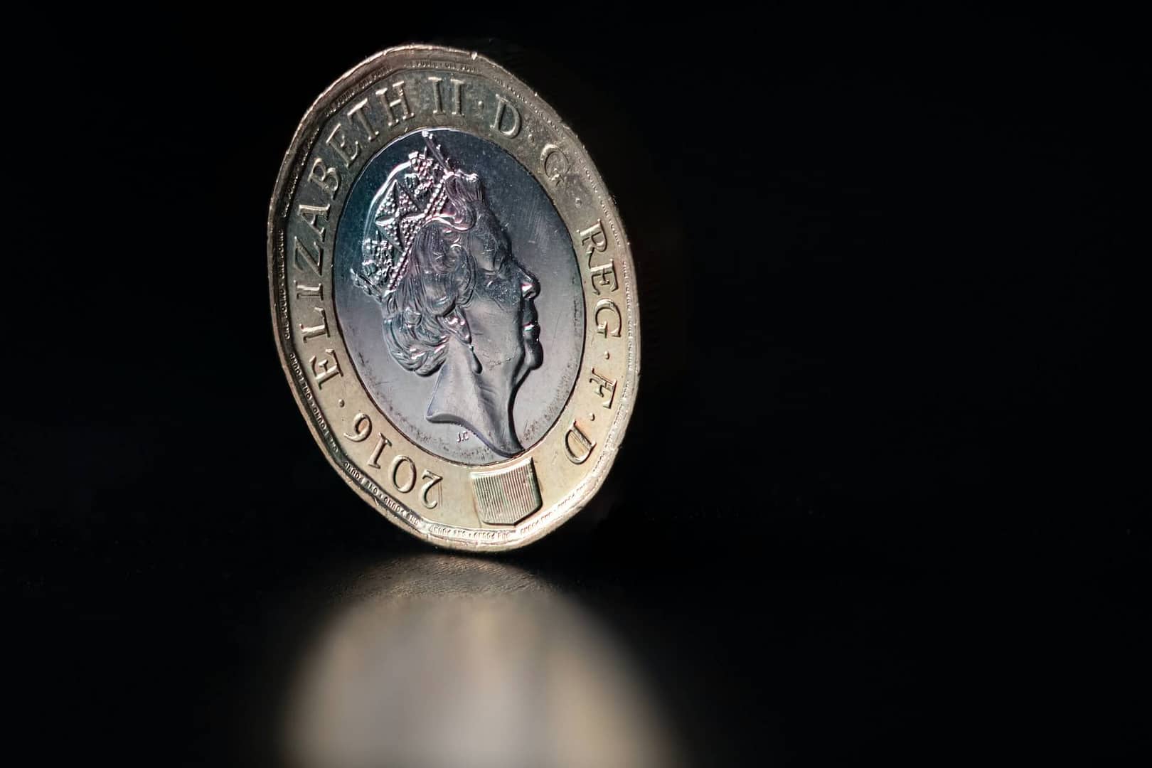 A stood up pound coin against a dark background