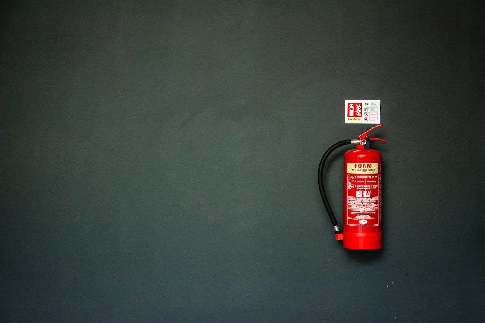 A red fire extinguisher against a dark wall