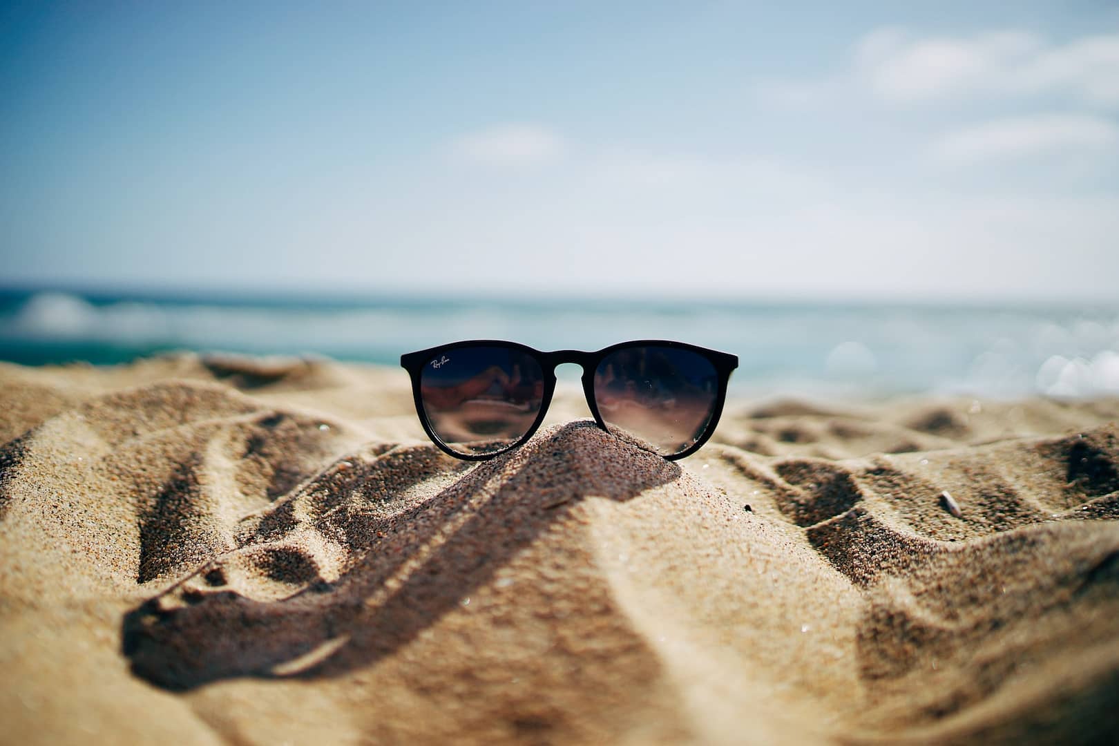 sunglasses resting on sand on the beach