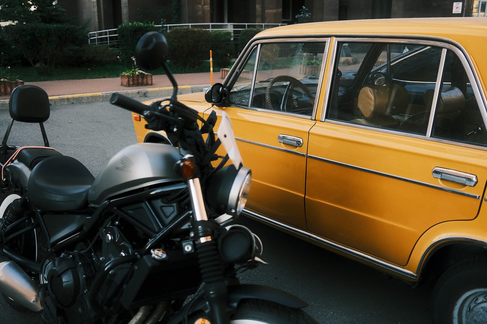 a car and motorbike next to each other in a car park