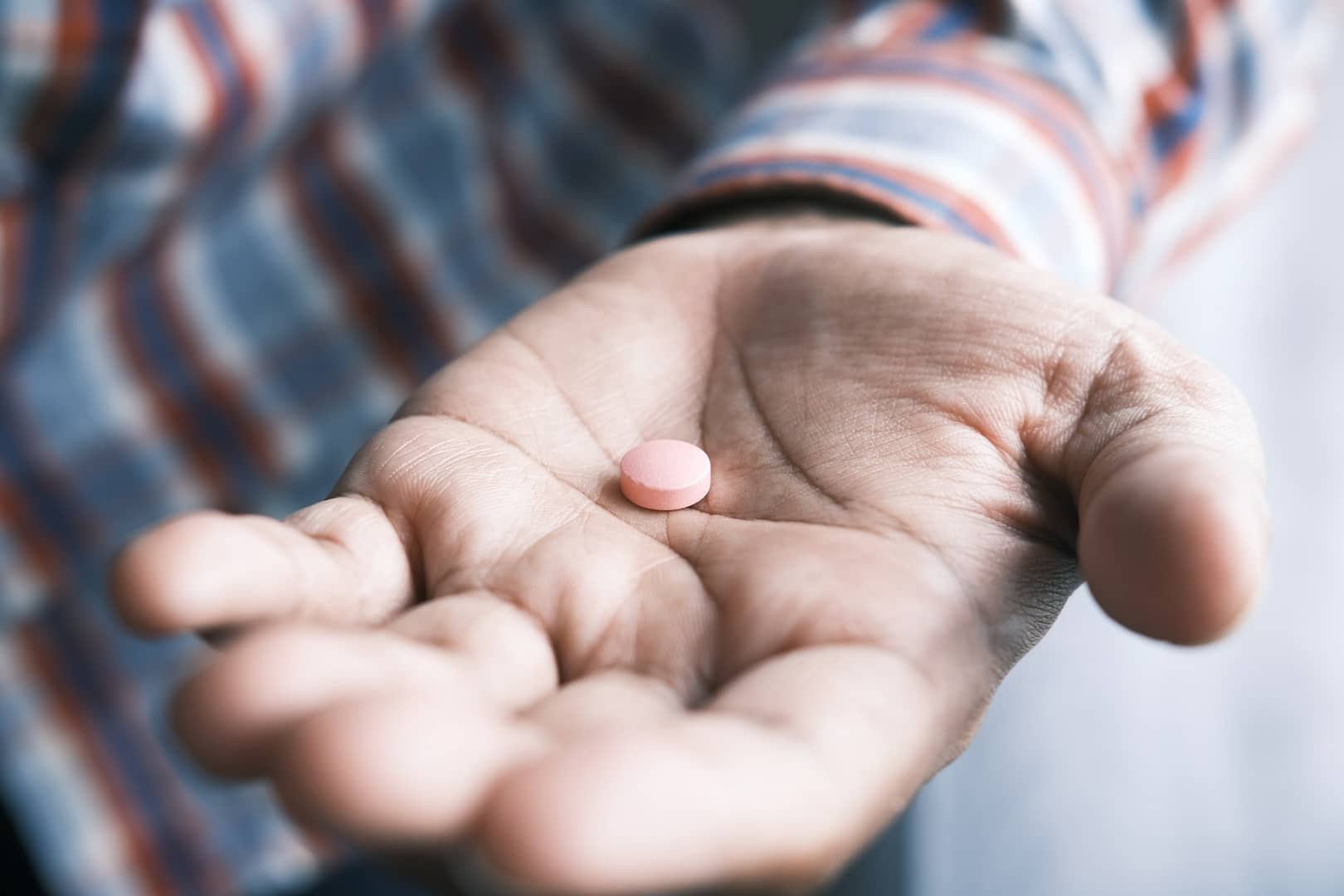 someone looking at a pill in their hand