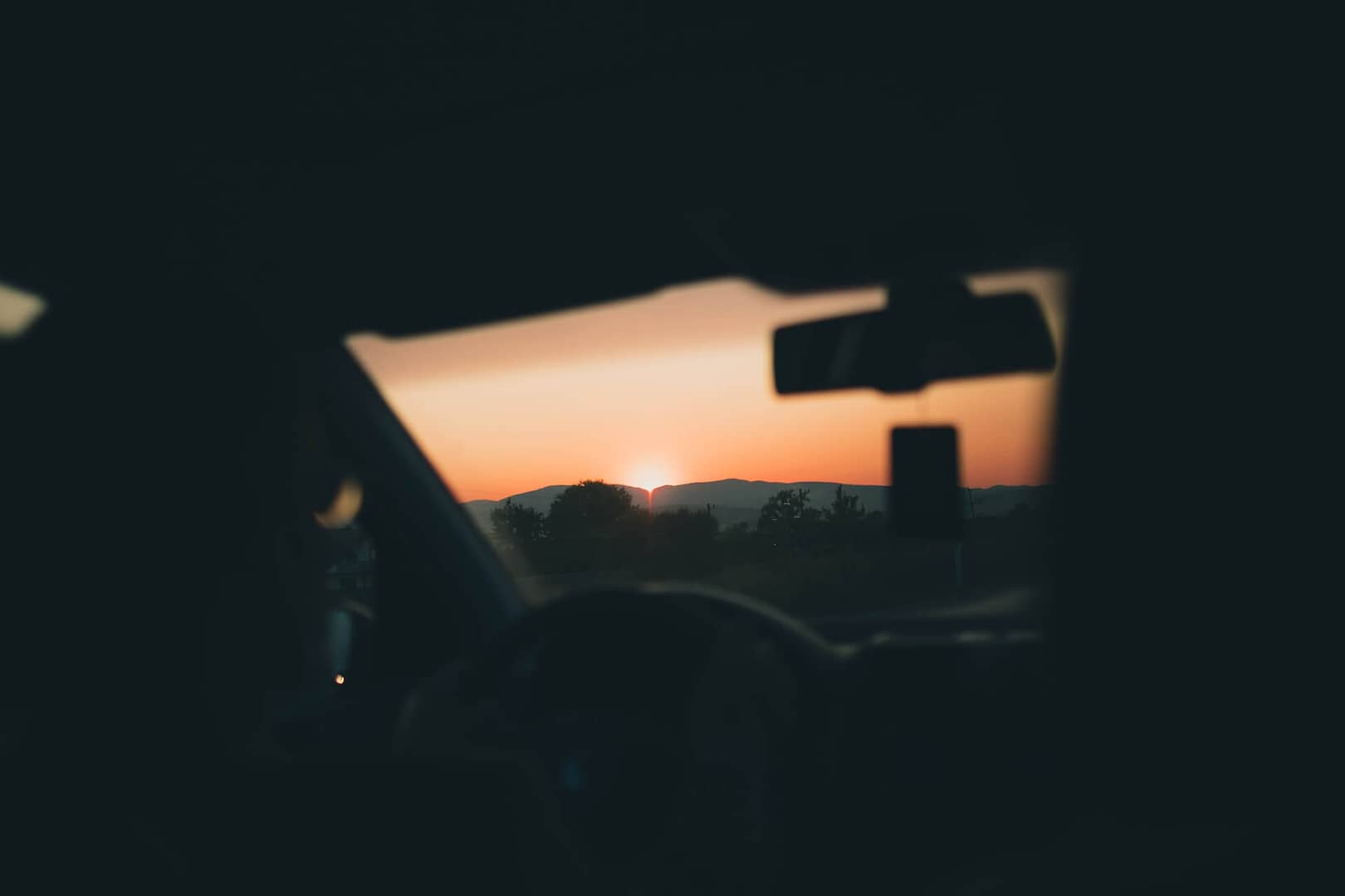 Sun setting from the perspective of the front of a car