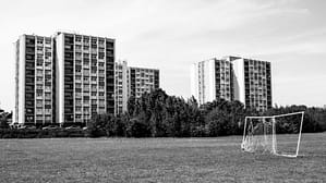 black and white photo of two blocks of high rise flats behind a football net.