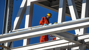 A builder in orange high visibility clothes a top a white building