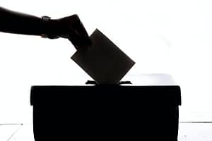 A silhouette of someone putting their ballot paper in the ballot box