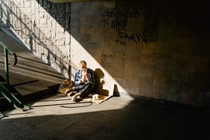 A homeless person sitting at the bottom of stairs