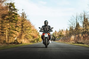 Someone riding a motorbike through a road surrounded by forest