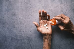 An elderly person pouring pills into their hand