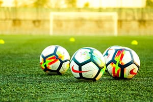 Three footballs on a pitch