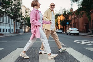 two elderly people crossing the road