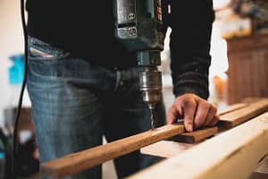 Someone using an electric drill with some wood