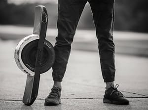 someone standing next to a onewheel e skateboard