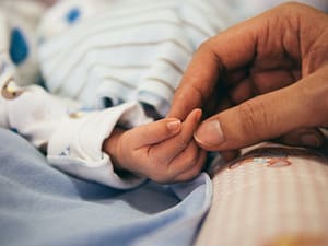 a new born baby holding onto their parents hand