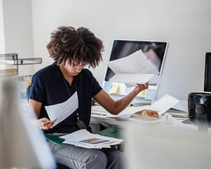 Someone looking stressed whilst looking at a number of documents