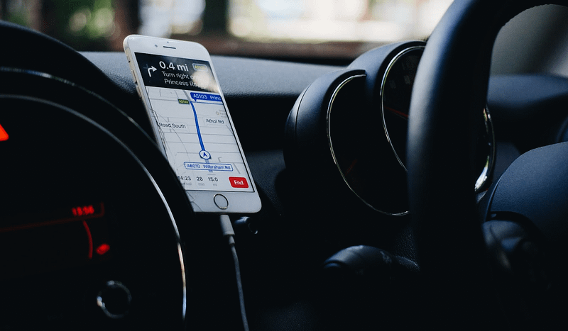 A phone giving directions next to a steering wheel