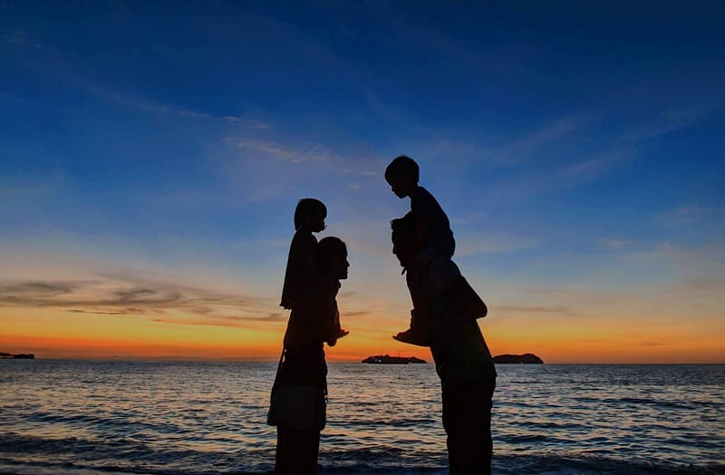 A family at a beach at sunset