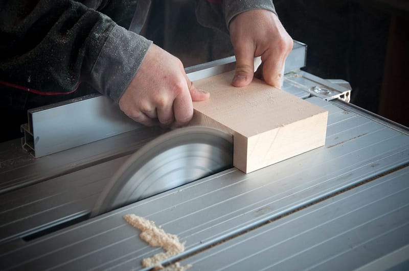 Someone using an electric saw with a block of wood