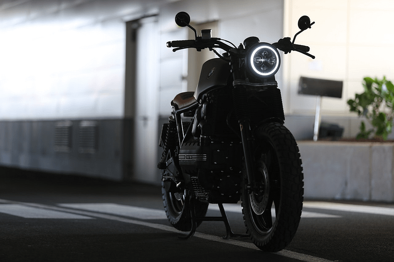 A motorbike parked in a dark tunnel lit up by its headlight