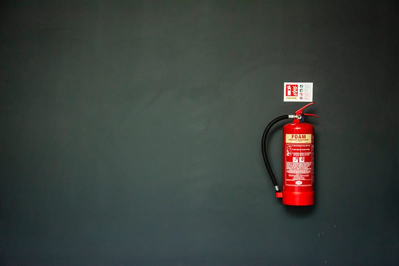 A red fire extinguisher against a dark wall