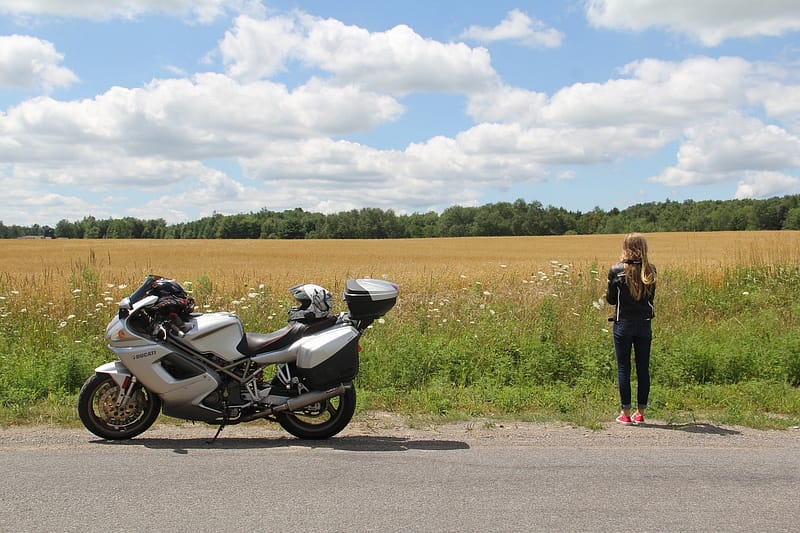 Someone looking out onto a farm with their motorbike parked by the side of the road