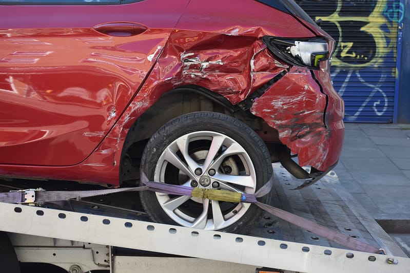 A dented rear wheel on a car being loaded onto the back of a recovery van