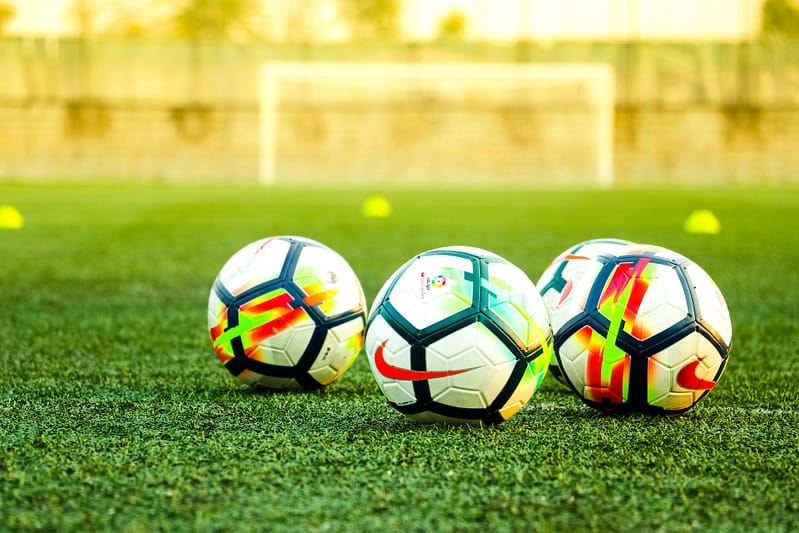 Three footballs on a pitch