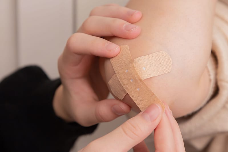 Someone applying a plaster on someones elbow