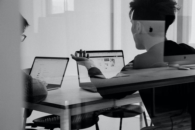 two people working on their laptops in an office