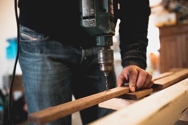 Someone using an electric drill with some wood