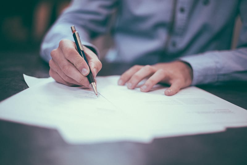 a man filling out paperwork with a black pen