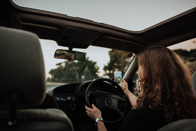 Someone on their phone in the driving seat of a car