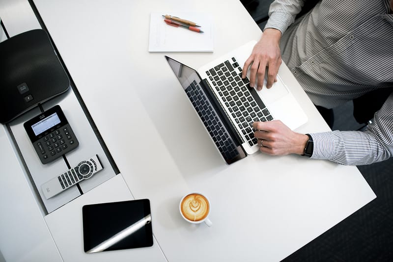 Someone at a desk with a laptop and coffee