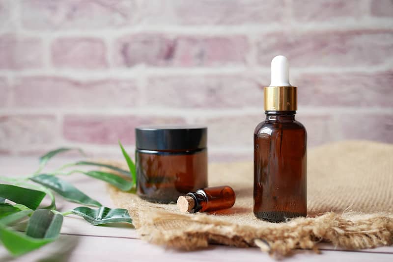 eucalyptus essential oils in a glass bottle with green leaf on white background