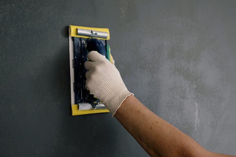 Someone sanding a wall