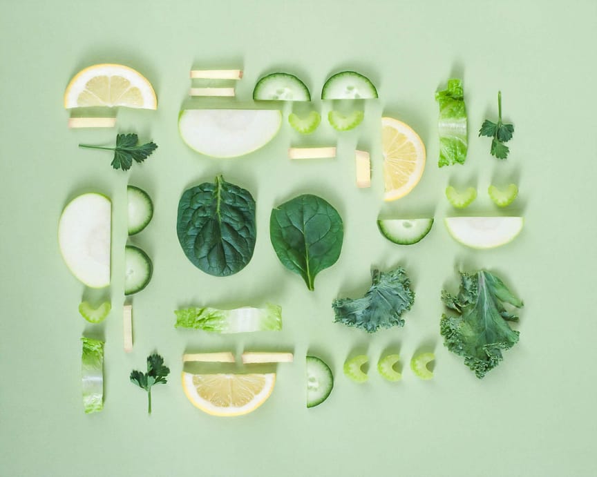 Different fruits and vegetables sliced against a green background